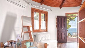 A cozy room with a wooden ceiling, a bed, a table with a kettle and cups, and a view of the sea through a door. - Solemar Sicilia - Residence Mer et Soleil (Bagheria)
