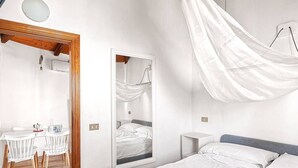 A bedroom with a bed, a bedside table, a mirror, and a hanging canopy. - Solemar Sicilia - Residence Mer et Soleil (Bagheria)