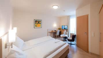 Una habitación de hotel con una cama grande, un escritorio, una silla y un televisor.