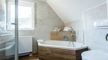 A modern bathroom with a freestanding bathtub, a glass shower enclosure, and a toilet.