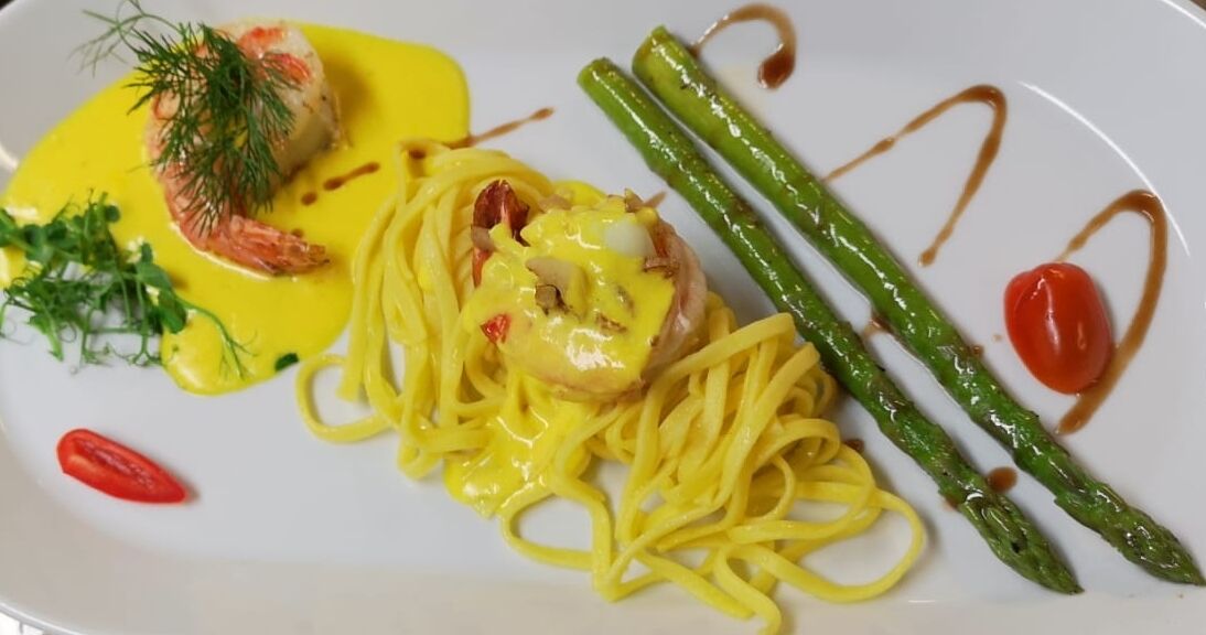 Eine Portion Pasta mit Garnelen, Spargel und einer Kirschtomate.