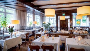 A restaurant with multiple tables set for dining, featuring a brick floor and wooden beams on the ceiling.