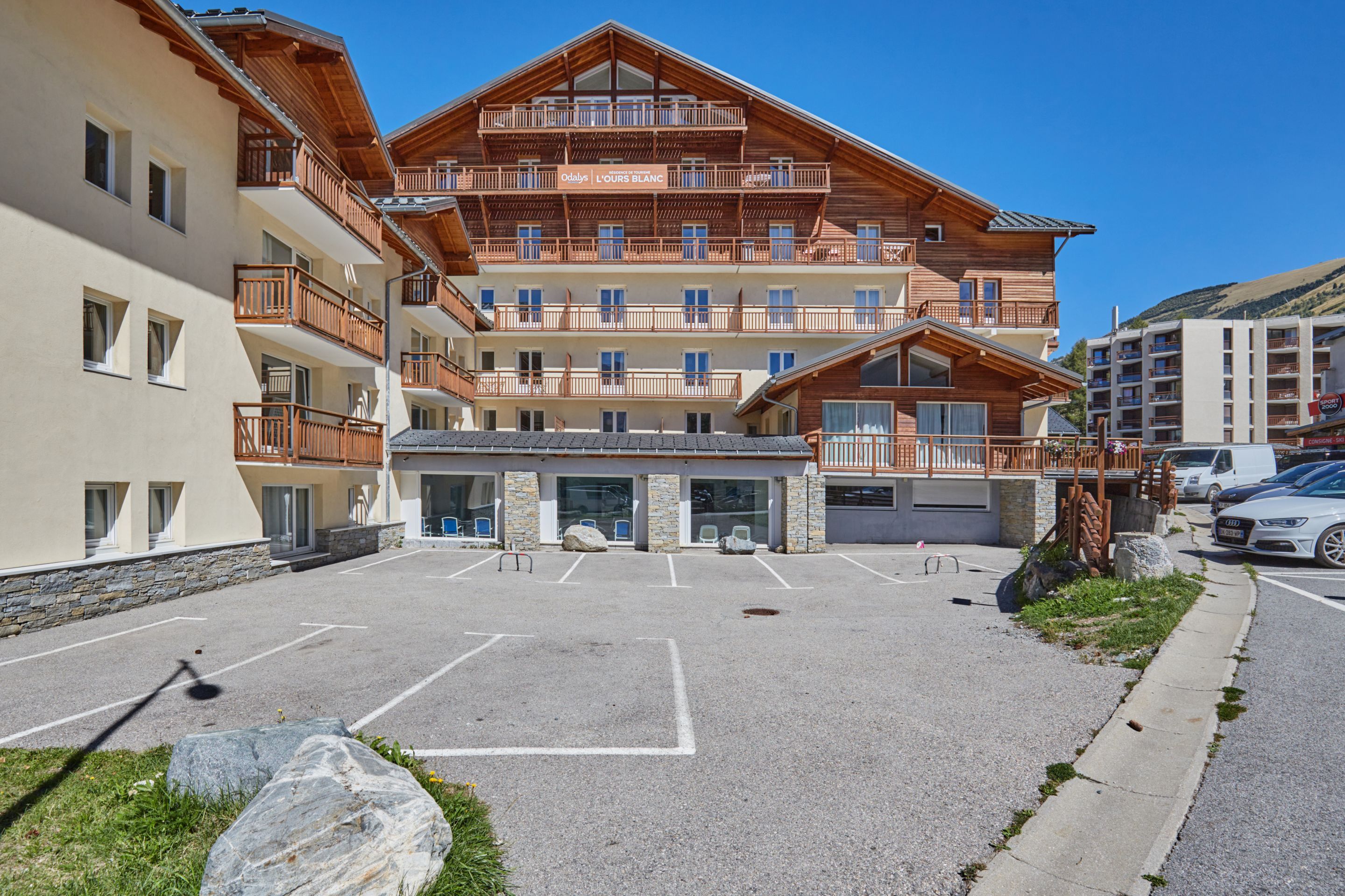 Ein mehrstöckiges Hotel mit Balkonen, einem Parkplatz und einer Stein-Fassade.