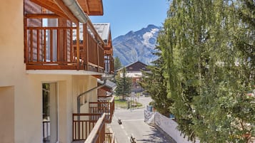 A wooden building with balconies overlooking a street and a mountain in the background.