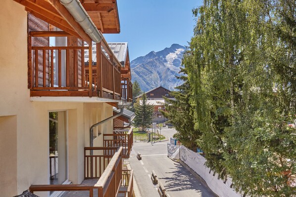 Un edificio de madera con balcones que dan a una calle y una montaña al fondo.
