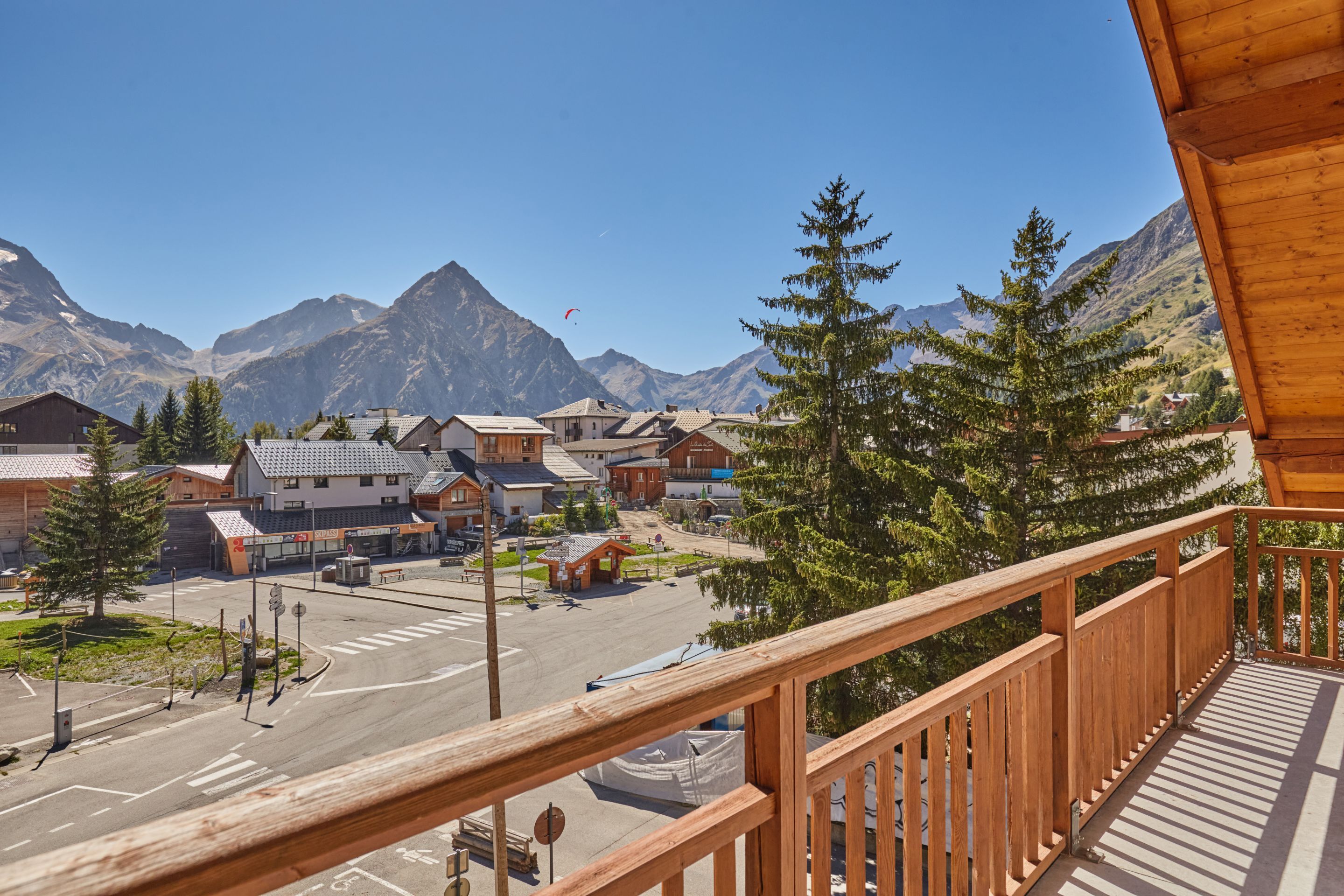 A mountain village with wooden buildings, a clear road, and a view of snow-capped mountains.