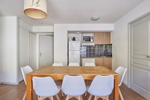 Une cuisine moderne avec des meubles blancs, un four à micro-ondes et un réfrigérateur.
