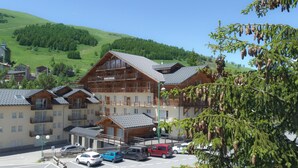 Un hôtel doté de nombreux balcons, d’un parking et offrant une vue sur une colline verdoyante.