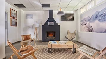 Ein gemütliches Zimmer mit Kamin, Holzmöbeln und Kunstwerken an den Wänden.