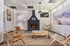 Een gezellige kamer met een open haard, houten meubels en kunstwerken aan de muur.
