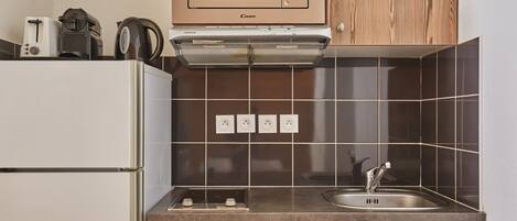 A compact kitchen with a microwave, toaster, kettle, and a dishwasher.