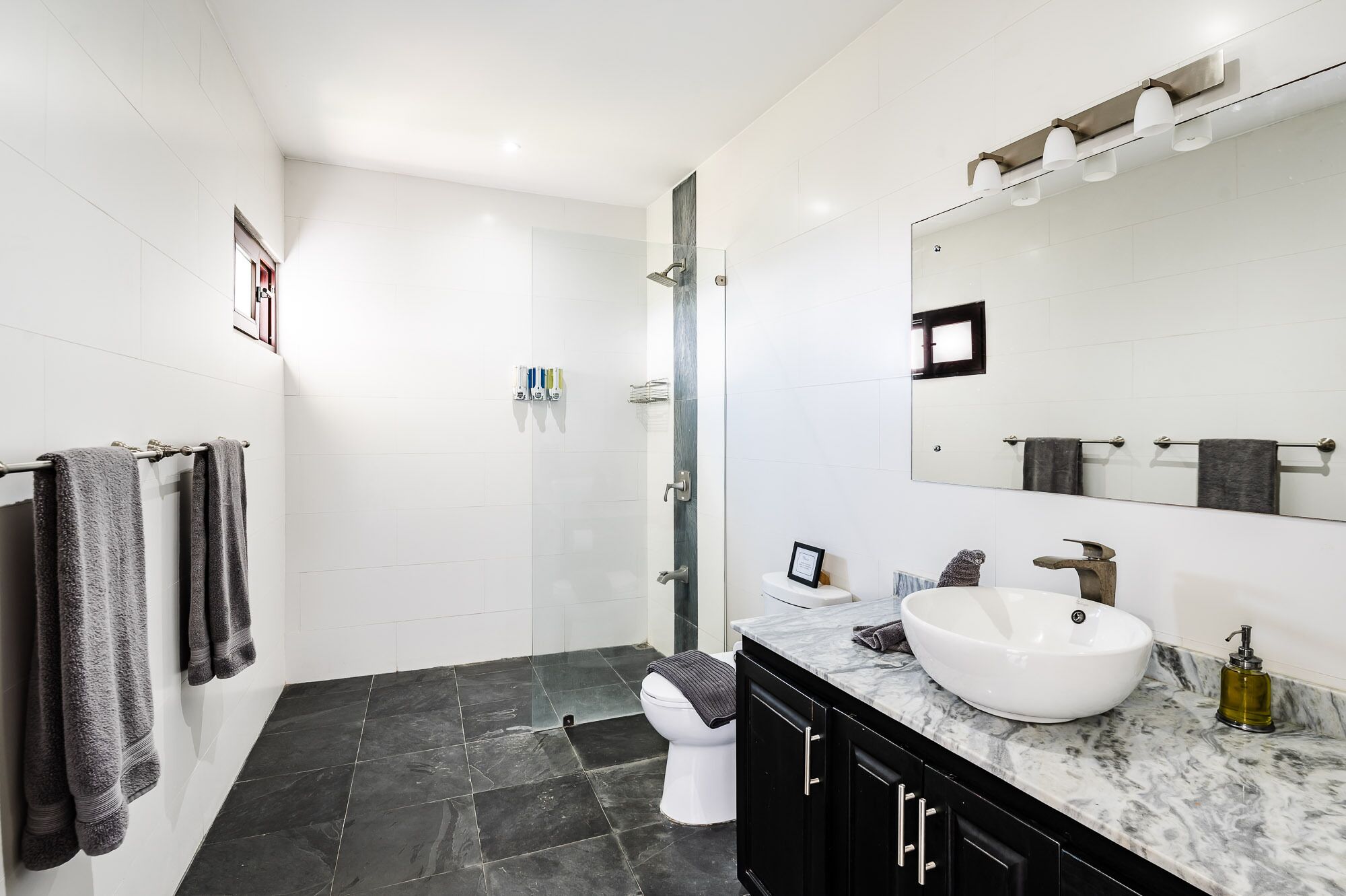 A modern bathroom with a large mirror, a white sink, and a shower area.