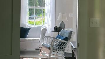 Une pièce avec une fenêtre, un canapé, une chaise, une petite table et un tapis.