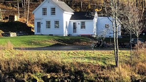 A white house with a chimney, a small shed, and a river in the foreground. - “STEP BACK IN TIME” 1880’ charmer.<br>Riverside Cottage<br> entire house (Warren)