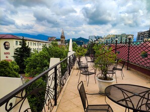 A rooftop terrace with outdoor seating, a view of city buildings, and a distant church spire. - OLD CITY Boutique Hotel (Batumi)
