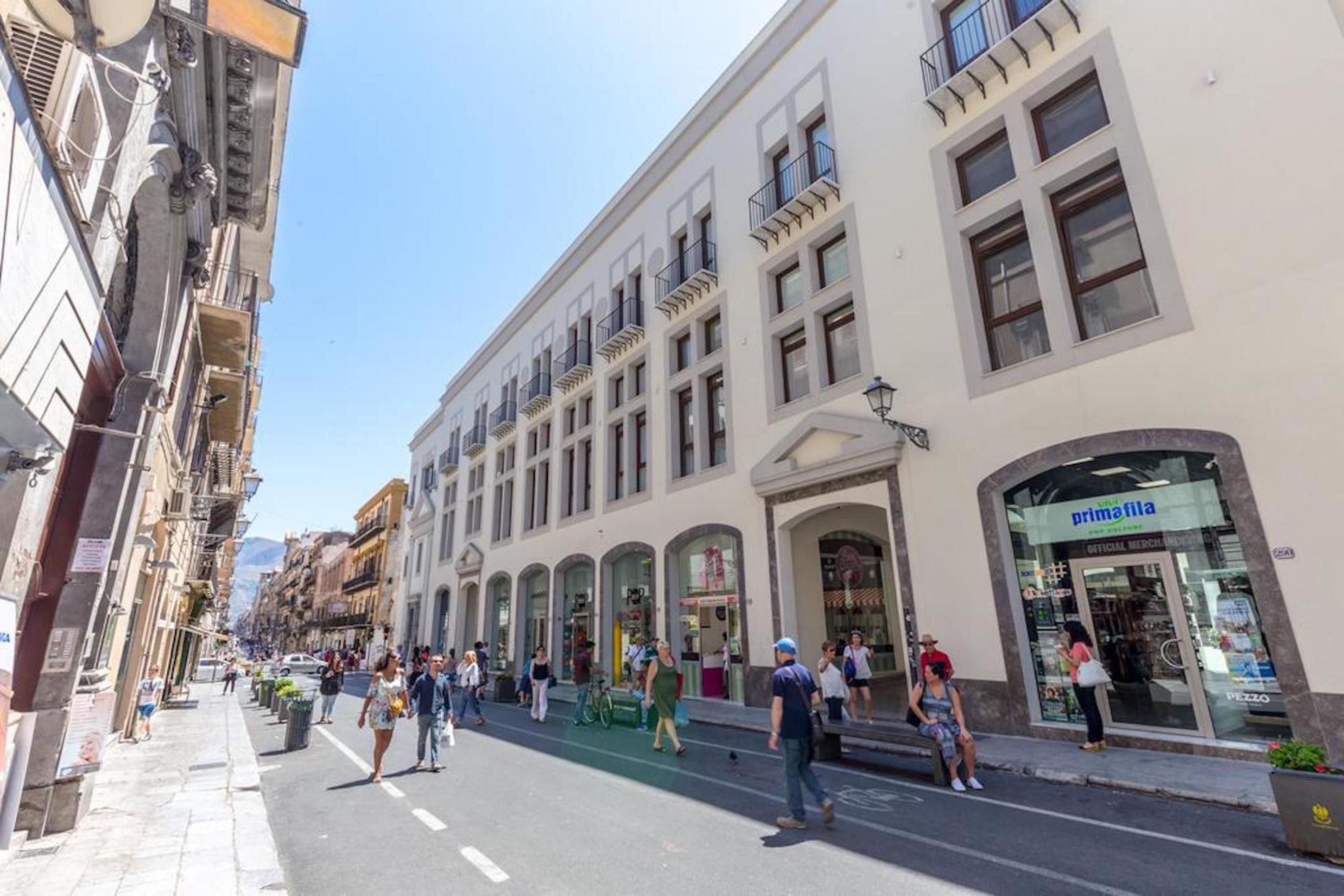 Un carrer amb vianants, un edifici amb aparador, i un cel serè.