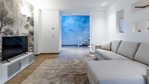 A modern living room with a flat-screen TV, a beige sofa, and a patterned wall. - Solemar Sicilia - Galleria Maqueda (Palermo)