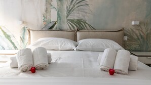 A neatly made bed with white linens and two rolled towels with red rose decorations. - Solemar Sicilia - Galleria Maqueda (Palermo)