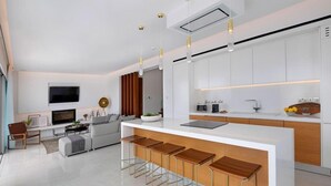 A modern kitchen with a central island, bar stools, and a dining area. - Golden Shore (Pegeia)