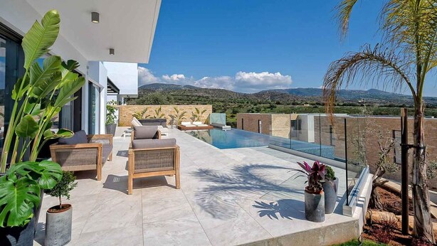 A modern outdoor living area with a pool, seating, and potted plants. - Golden Shore (Pegeia)