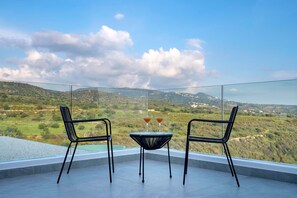 A balcony with two chairs and a table, overlooking a scenic landscape. - Golden Shore (Pegeia)