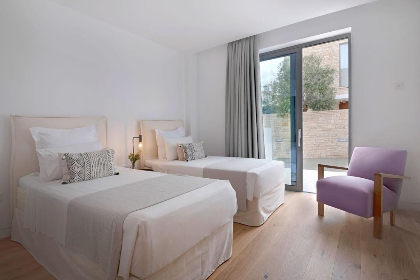 Ein Hotelzimmer mit zwei Betten, einem Sessel und einem großen Fenster mit Ausblick.