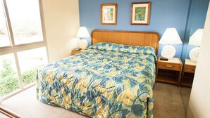 Un dormitorio con una cama grande, dos mesitas de noche con lámparas y dos cuadros enmarcados en la pared.