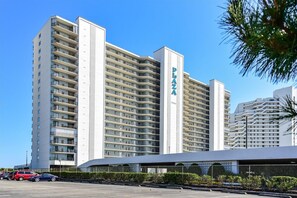 Een hoog hotel met meerdere balkons, een opvallend ‘Palo Alto’ bord en een parkeerplaats ervoor.