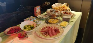 Una mesa de buffet con diversos alimentos, como frutas, quesos y productos de pastelería.