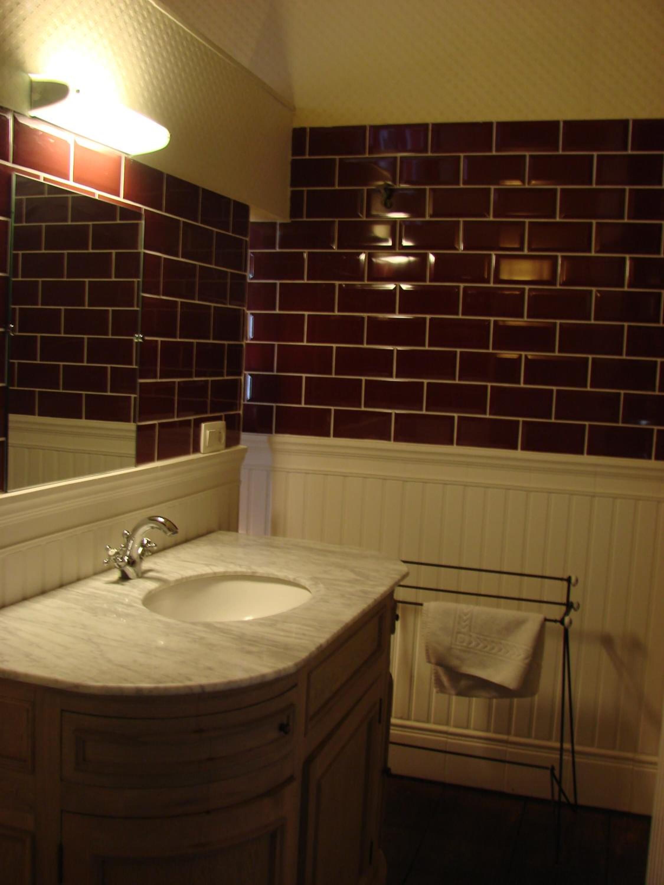 Une salle de bain avec un lavabo en marbre, un miroir et un porte-serviettes.