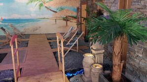 A beach-themed room with a wooden deck, lounge chairs, a palm tree, and a mural of a beach scene. - Hotel Góralski Wellness & SPA (Poronin)