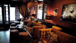 A dimly lit lounge with a sofa, ottomans, and a table with a candle. - Mojo Hotell (Örebro)