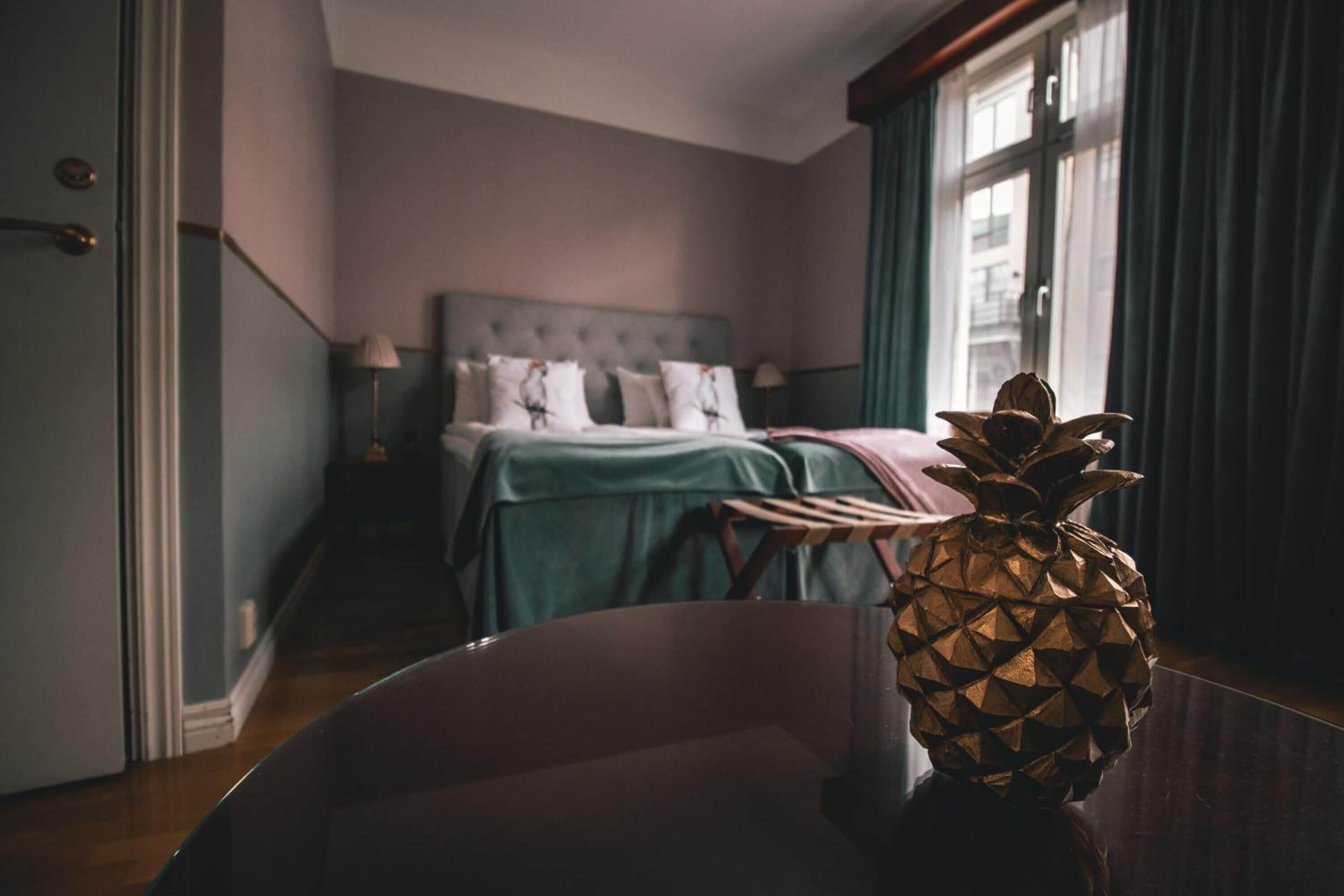 A hotel room with a bed, a chair, and a pineapple decoration.