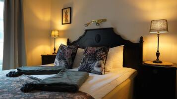 A neatly made bed with floral-patterned pillows and a dark headboard. There are two bedside lamps on either side of the bed.