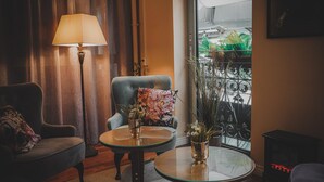 A cozy room with a sofa, armchair, and a small table with a lamp and flower vase. - Mojo Hotell (Örebro)