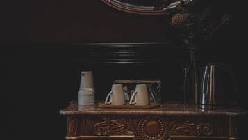 A dark wooden vanity with a round mirror, a stack of white cups, a white pitcher, and a kettle.
