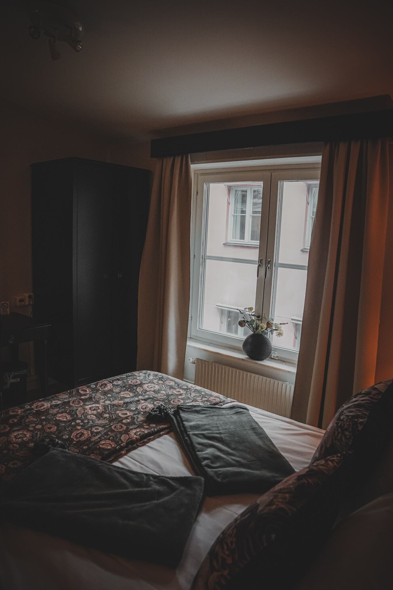 A bedroom with a bed, a dresser, and a window with curtains.