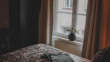 A bedroom with a bed, a dresser, and a window with curtains.