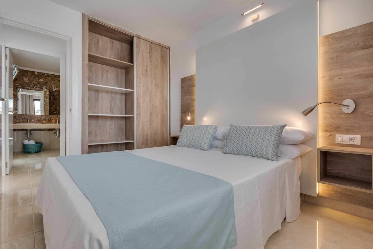 Un dormitorio moderno con una cama grande, estanterías empotradas y una pared de acento de piedra.