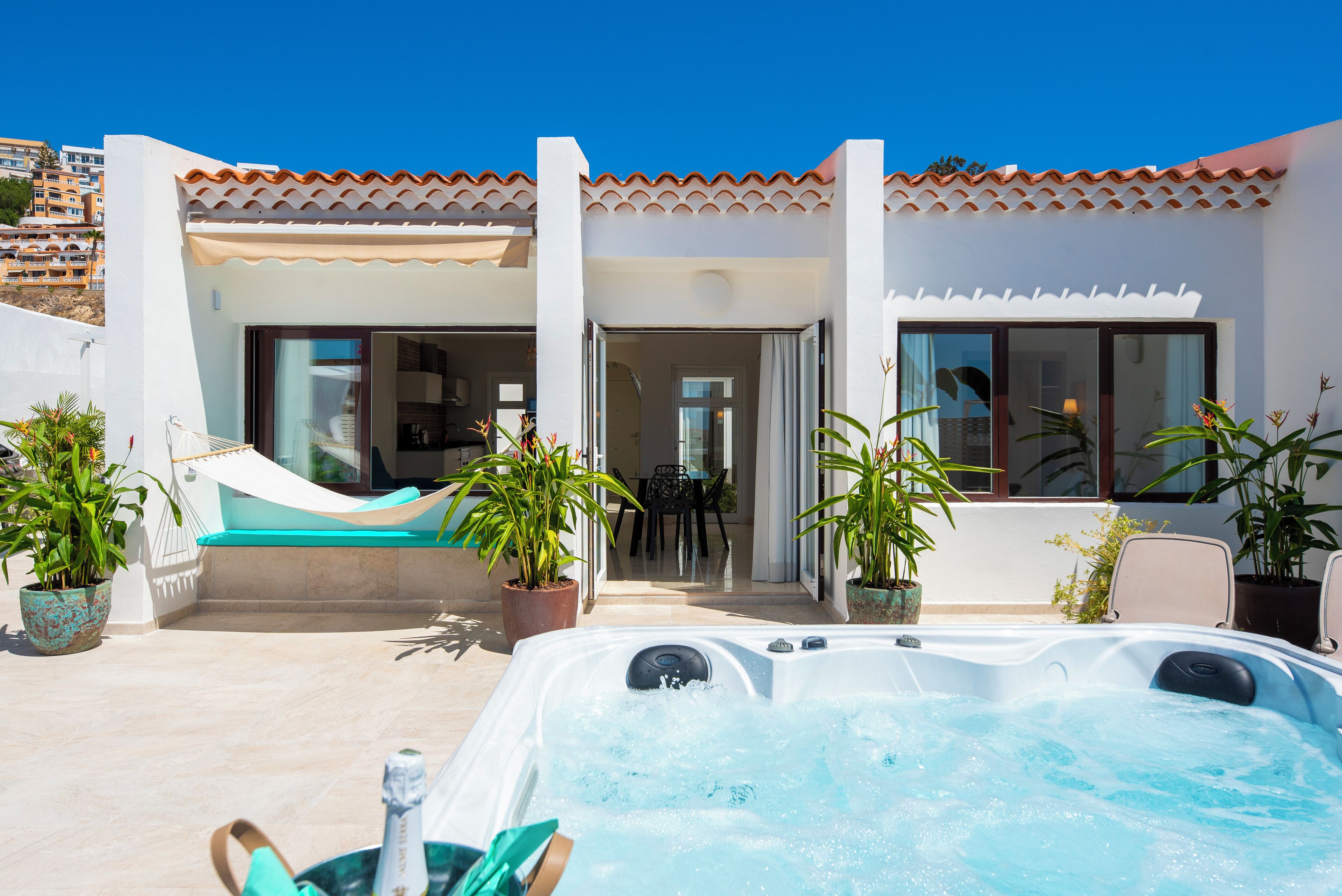 A pool area with a hot tub, outdoor seating, and potted plants.