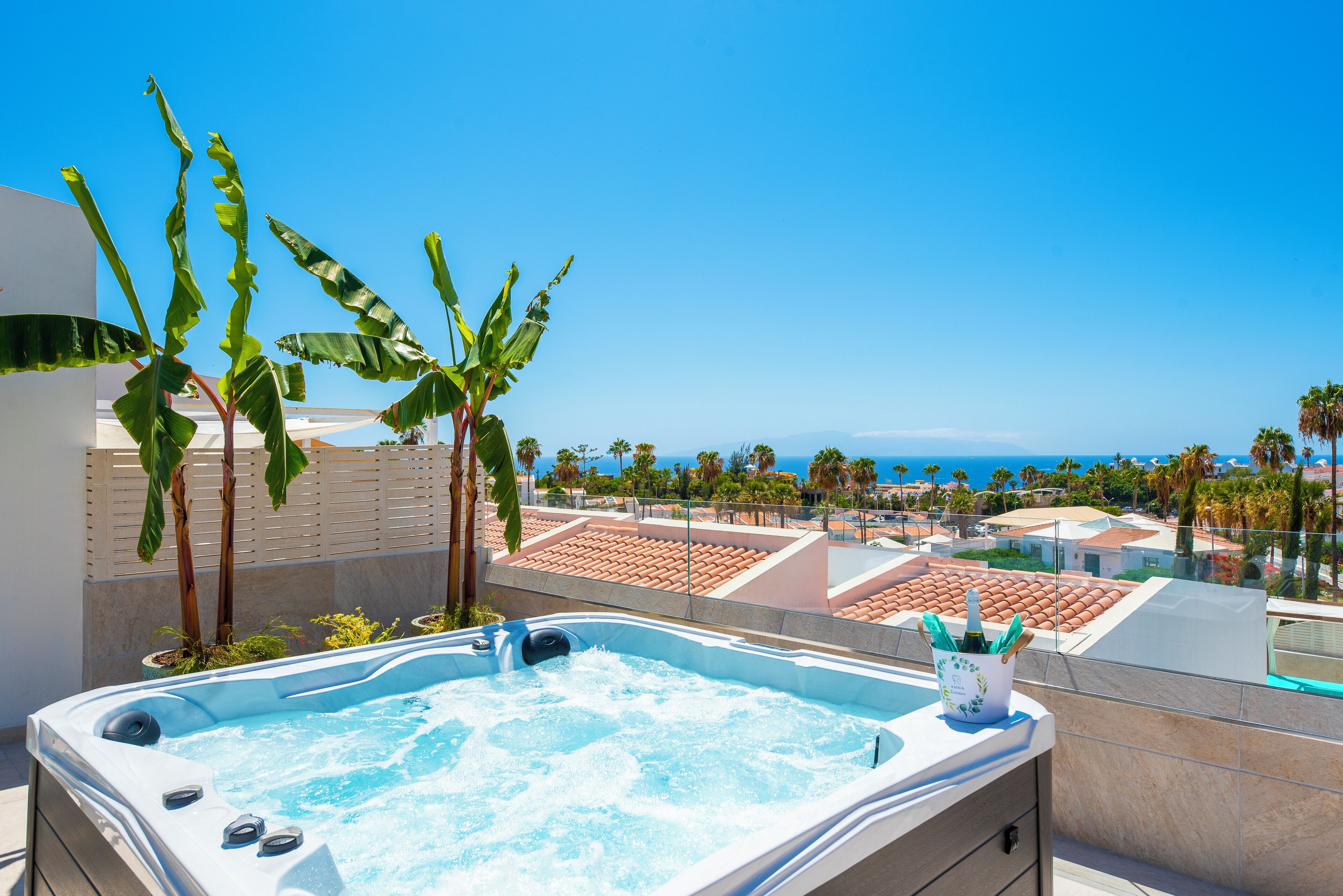 A hot tub with a clear view of the ocean and palm trees in the background.