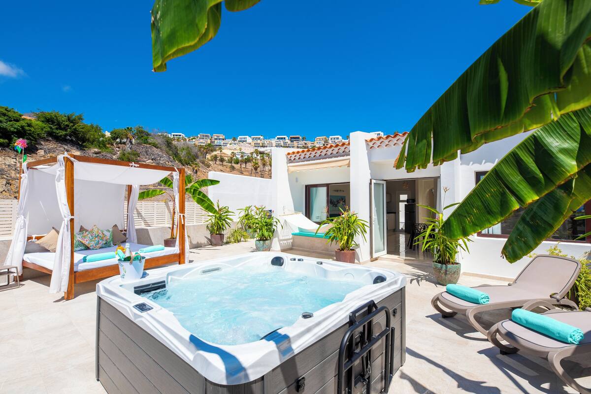 Área de piscina en la azotea con un jacuzzi, sillones de descanso y una cama con dosel.