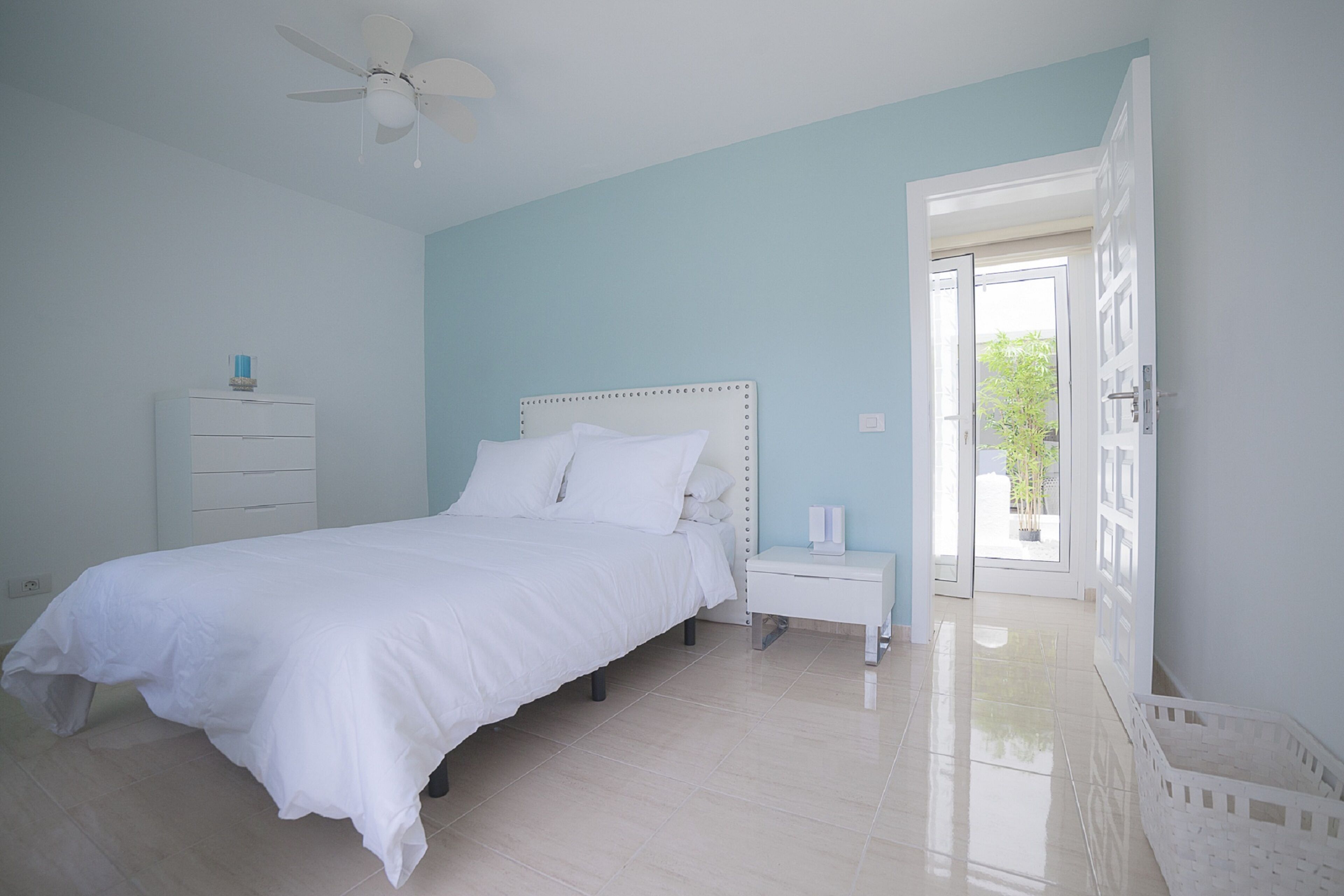 A bedroom with a bed, bedside table, and a ceiling fan.