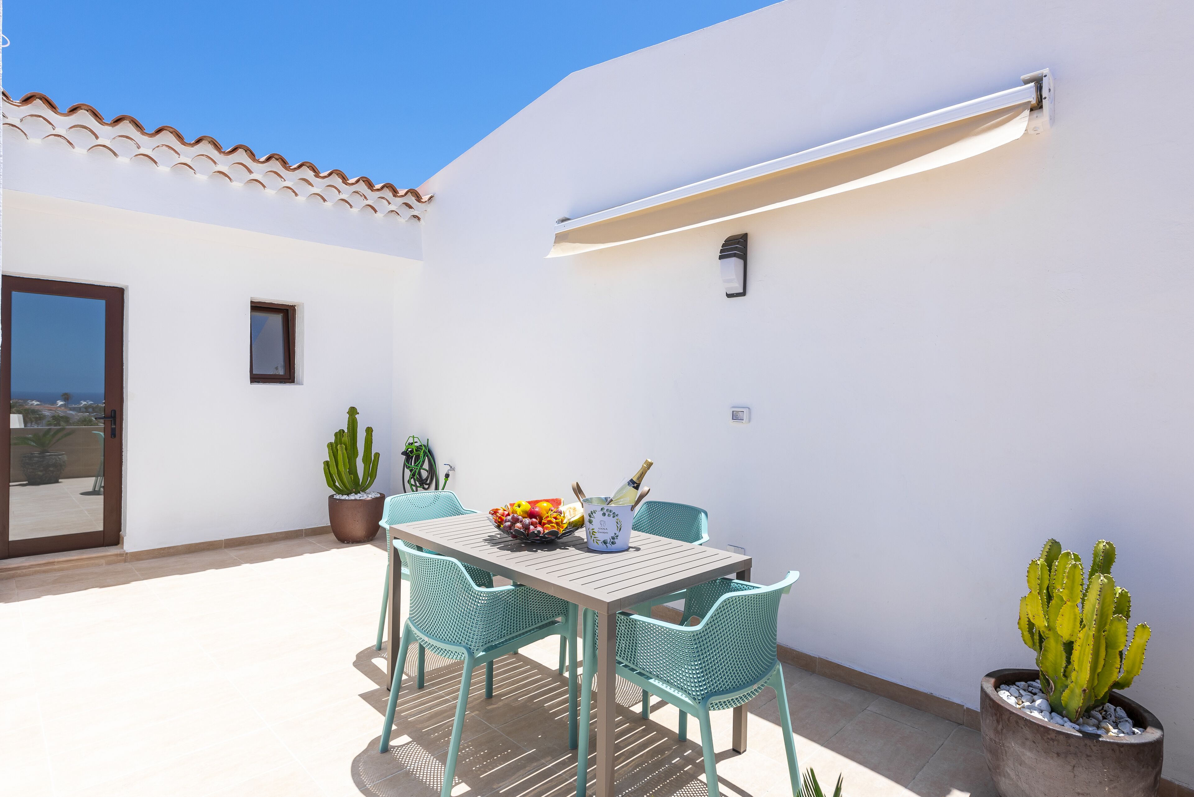 Une terrasse avec une table, des chaises et des plantes en pot.