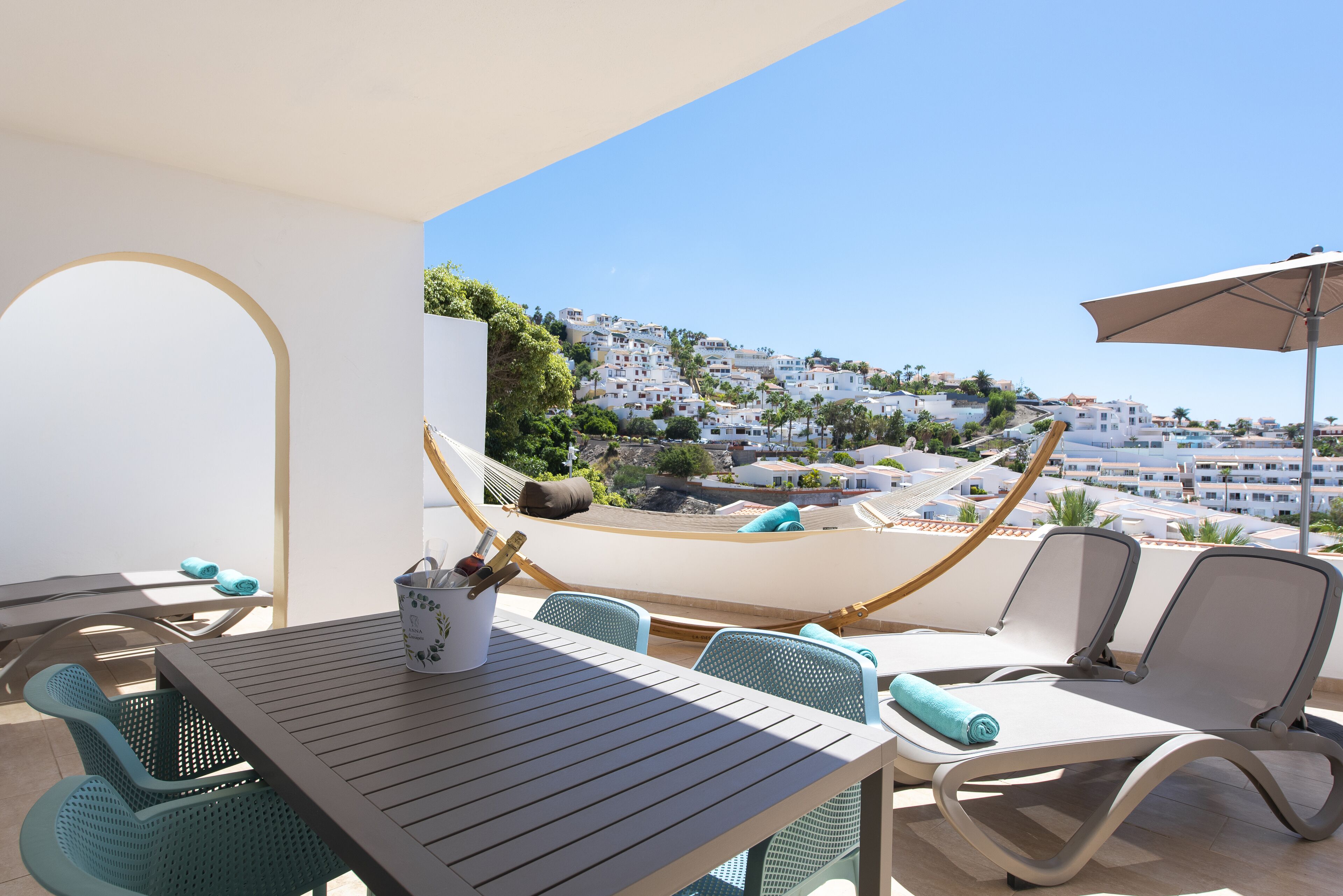 A balcony with a table, chairs, and a hammock.