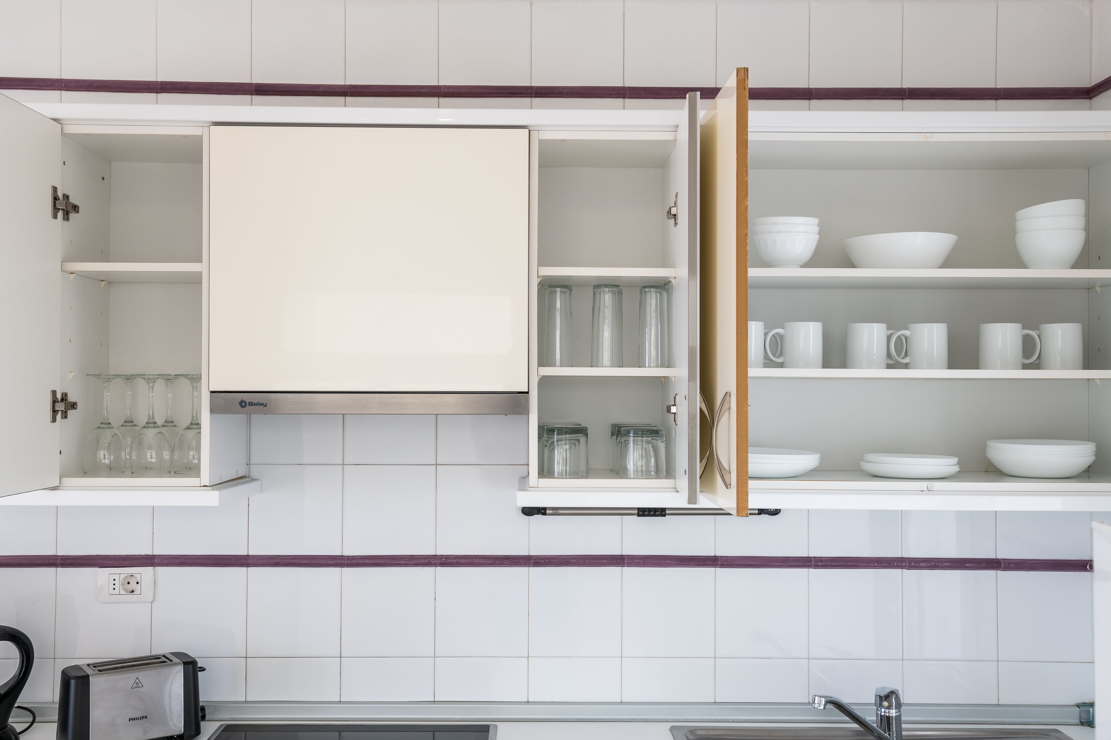 A kitchen with white cabinets, a toaster, and a sink.