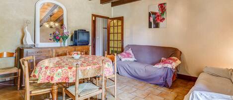 A cozy room with a wooden dining table, chairs, a sofa, and a television.