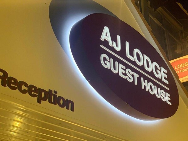 A sign for AJ Lodge Guest House, indicating a reception area.