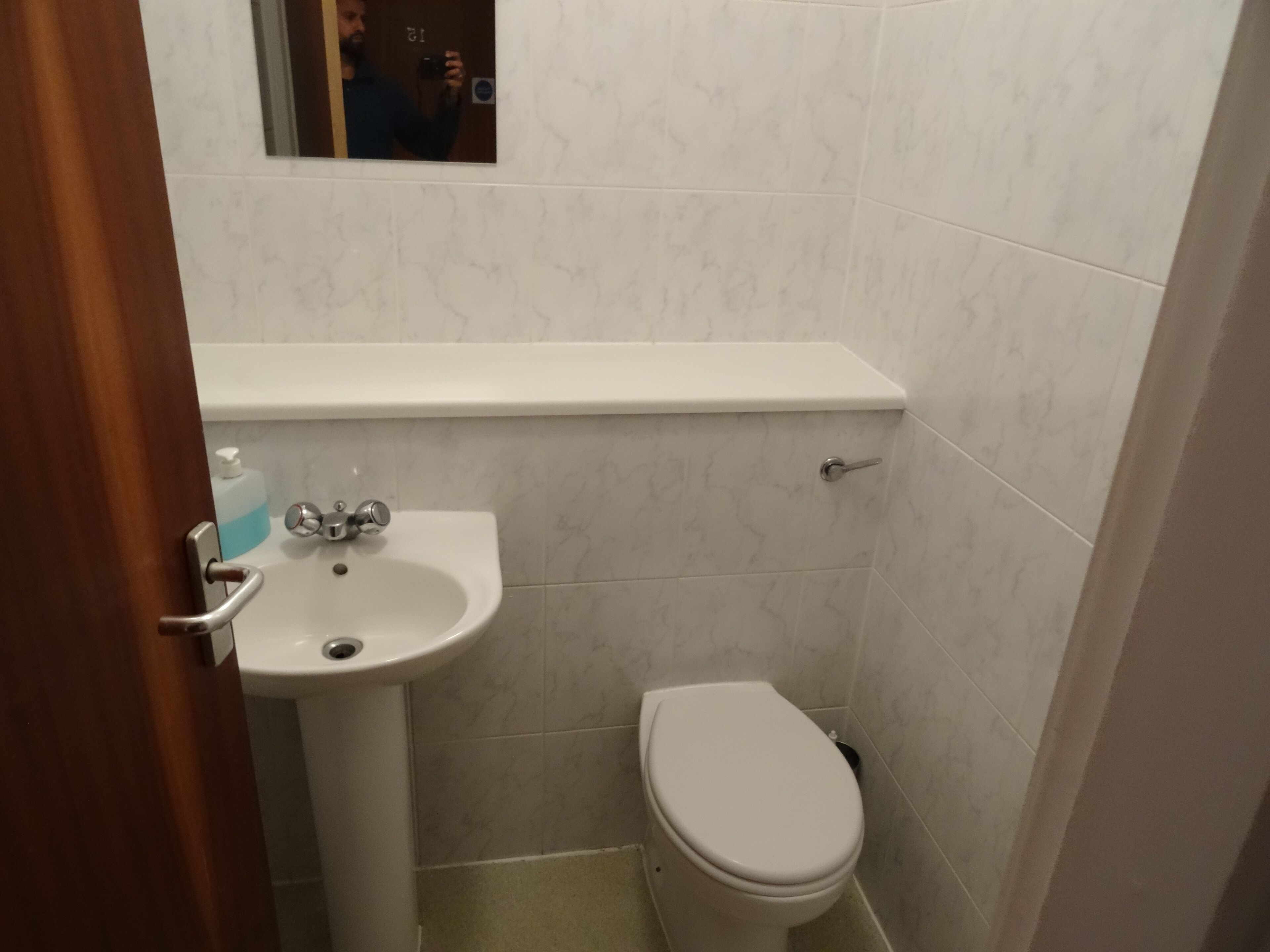 A small bathroom with a white sink, toilet, and a mirror above the sink.