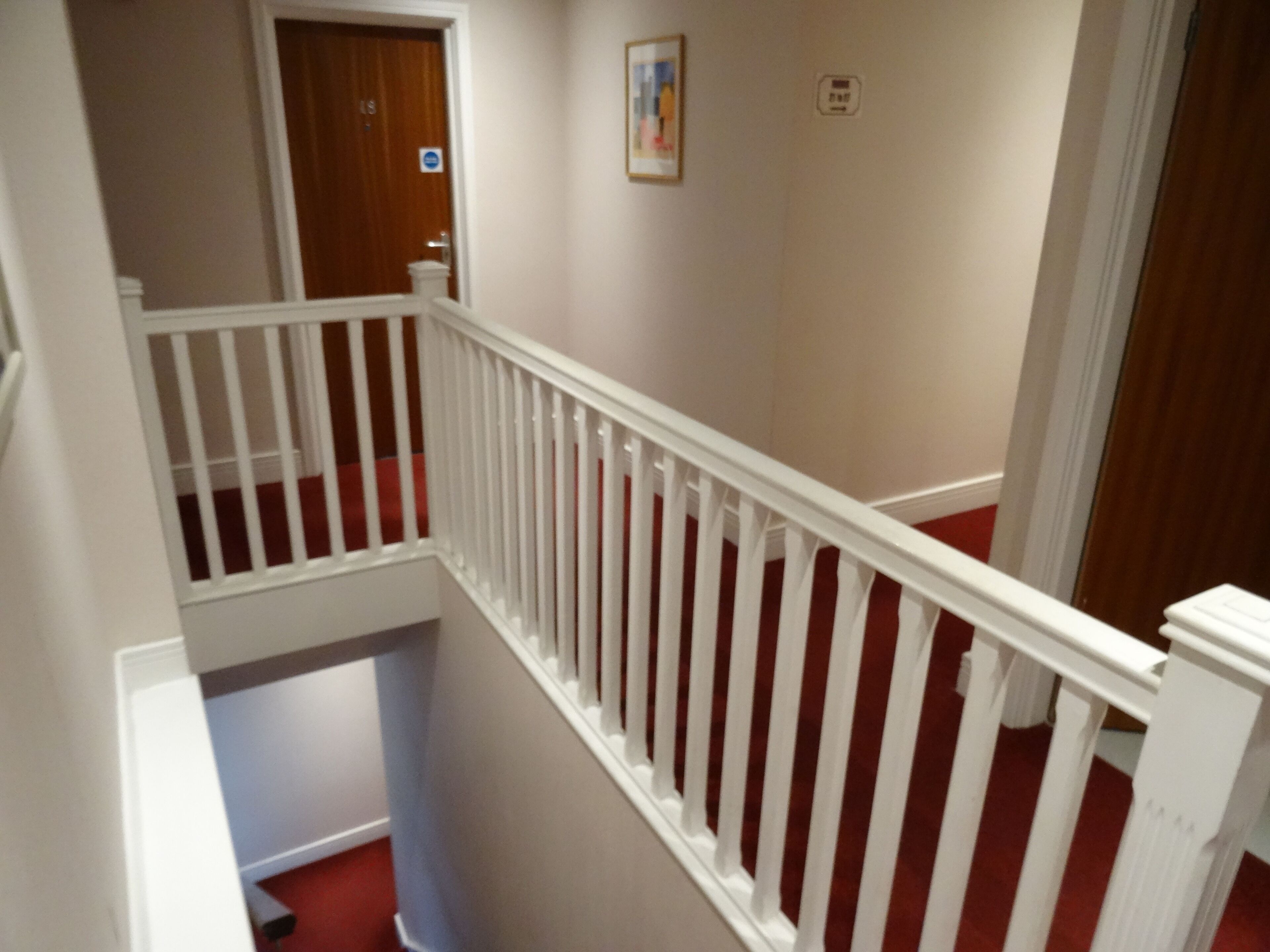 A staircase with white railings and red carpeted steps.